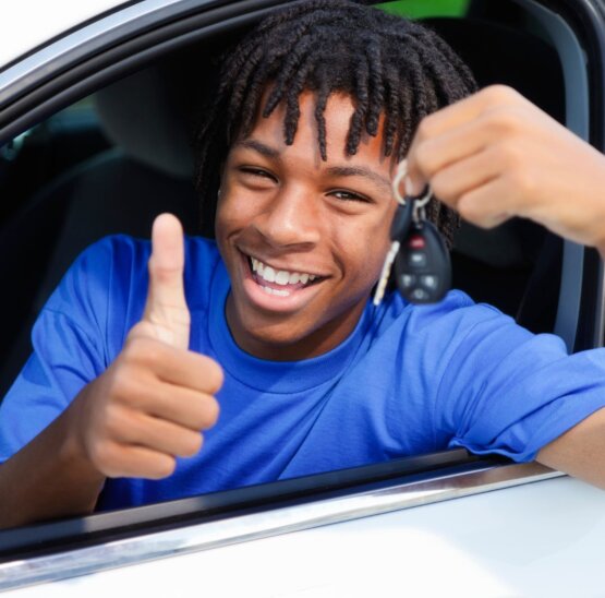Happy young teen in drivers seat celebrating that he passed his driver's test